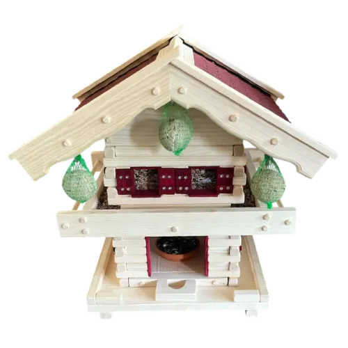 Zweistöckige Vogelvilla im alpinen Blockhaus-Stil aus hellem Holz mit Balkongeländer, rotem Schindeldach und drei aufgehängten Meisenknödeln