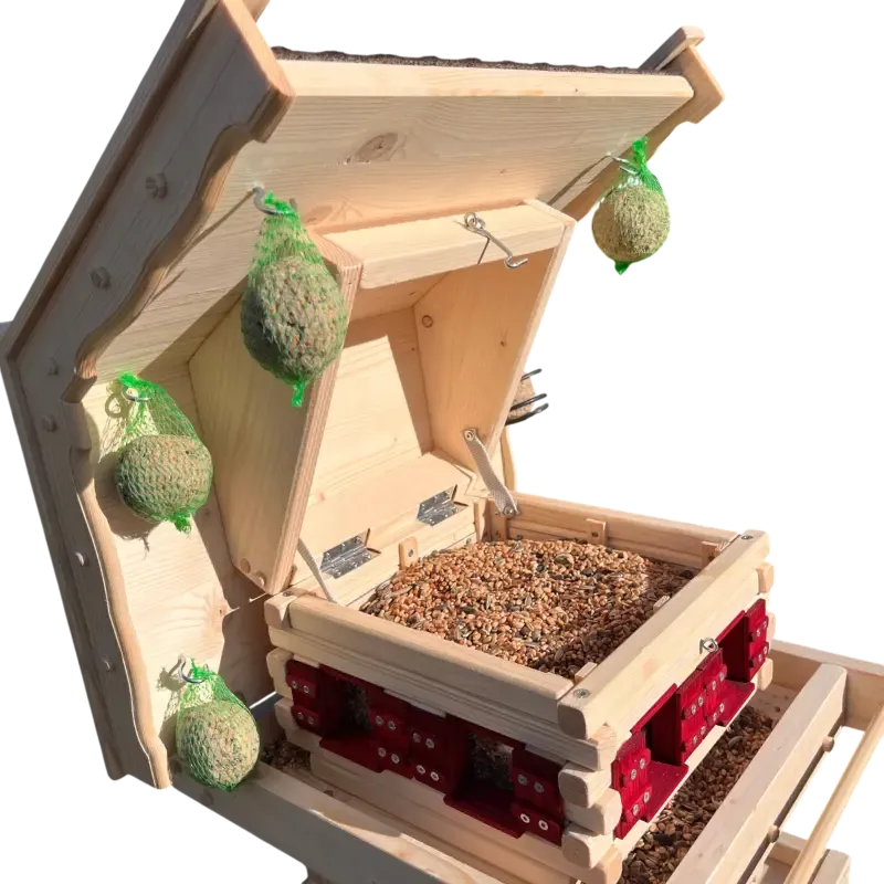 Innenansicht eines zweistöckigen Vogelfutterhauses mit geöffnetem Klappdach, befülltem Futtersilo und vier seitlich aufgehängten Meisenknödeln