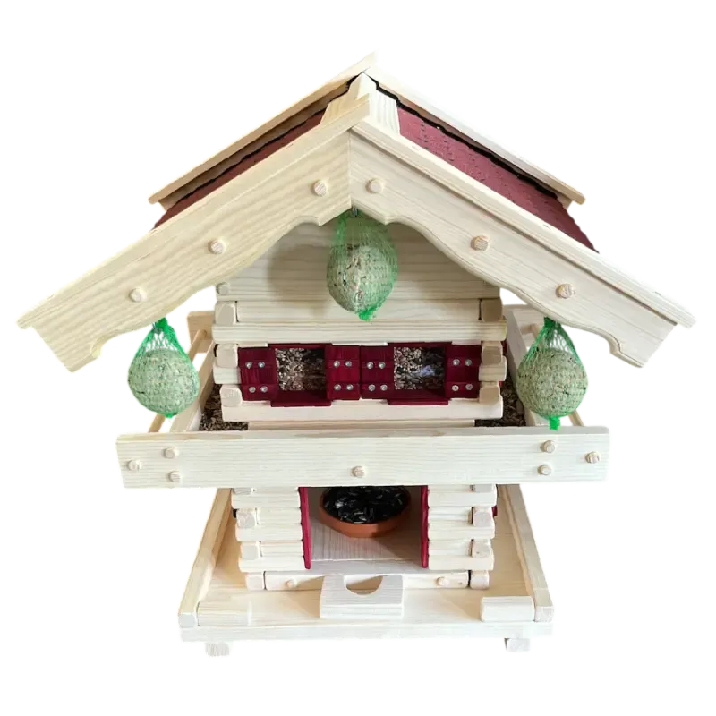 Zweistöckige Vogelvilla im alpinen Blockhaus-Stil aus hellem Holz mit Balkongeländer, rotem Schindeldach und drei aufgehängten Meisenknödeln